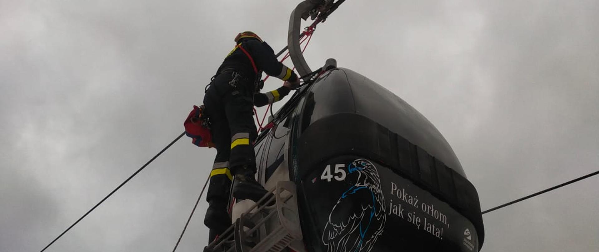 Strażak na linie przy wagoniku kolejki gondolowej