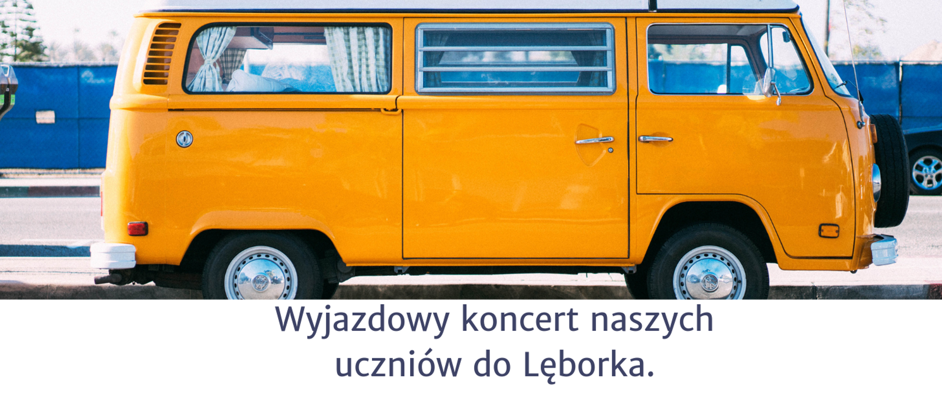 Zdjęcie przedstawia na pierwszym planie żółty samochód oraz informację o wyjeździe uczniów naszej szkoły do Lęborka na koncert.