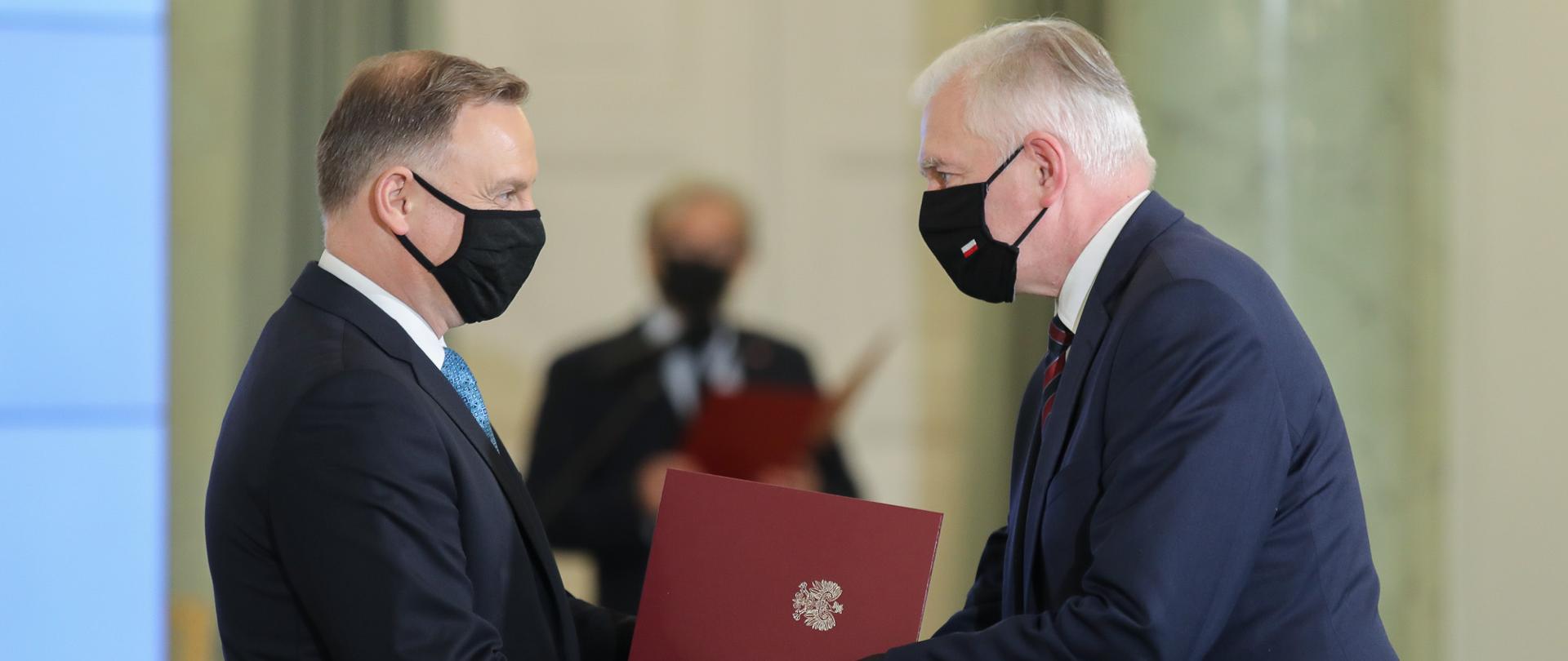 Andrzej Duda wręcza Jarosławowi Gowinowi teczkę z powołaniem.