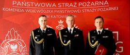 Śląski komendant wojewódzki pozuje do zdjęcia z komendantem powiatowym oraz nowym zastępcą komendanta powiatowego trzymającego decyzję