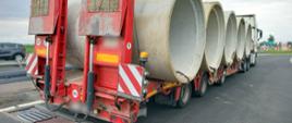 Na pierwszym planie nienormatywny zestaw ciężarowy z pięcioma dużymi rurami betonowymi. Ciężarówka stoi tuż za przenośnymi wagami ITD.