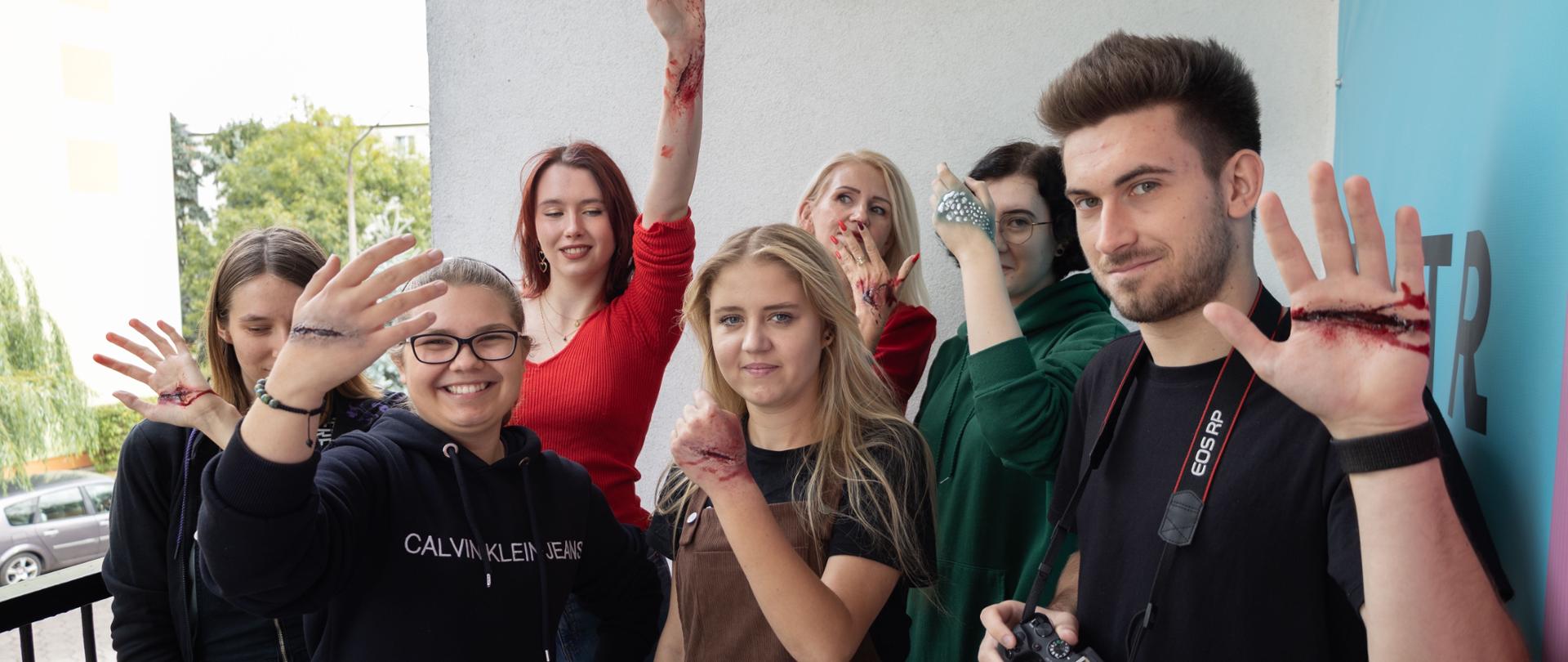 Grupa słuchaczy pozuje do zdjęcia z ranami na skórze, które zostały stworzone w procesie charakteryzacji podczas zajęć w Studium.
