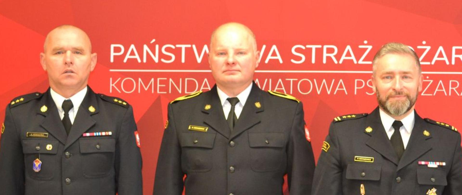 Strażak otrzymujący nagrodę z Komendantem i Dowódcą JRG w mundurach wyjściowych