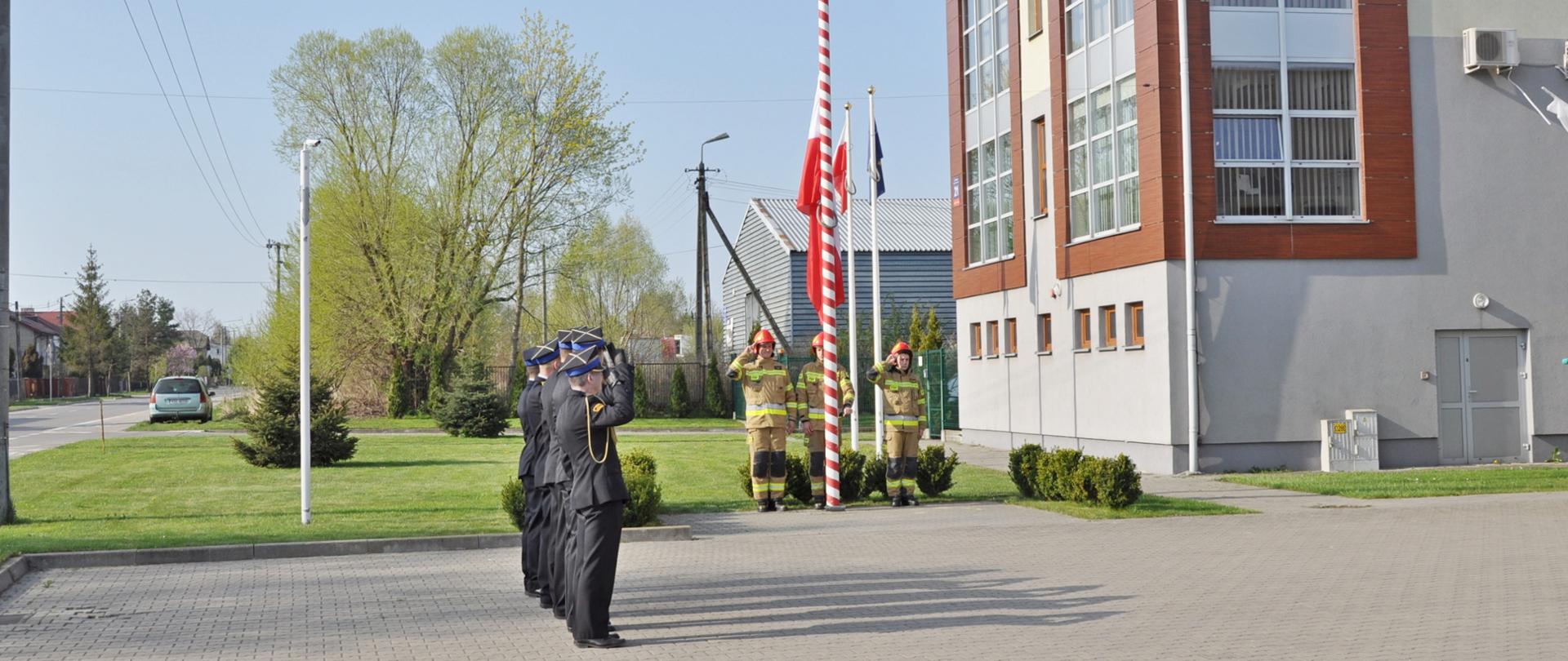 Uroczysta zbiórka z okazji święta flagi- strażacy stojący w strojach galowych.