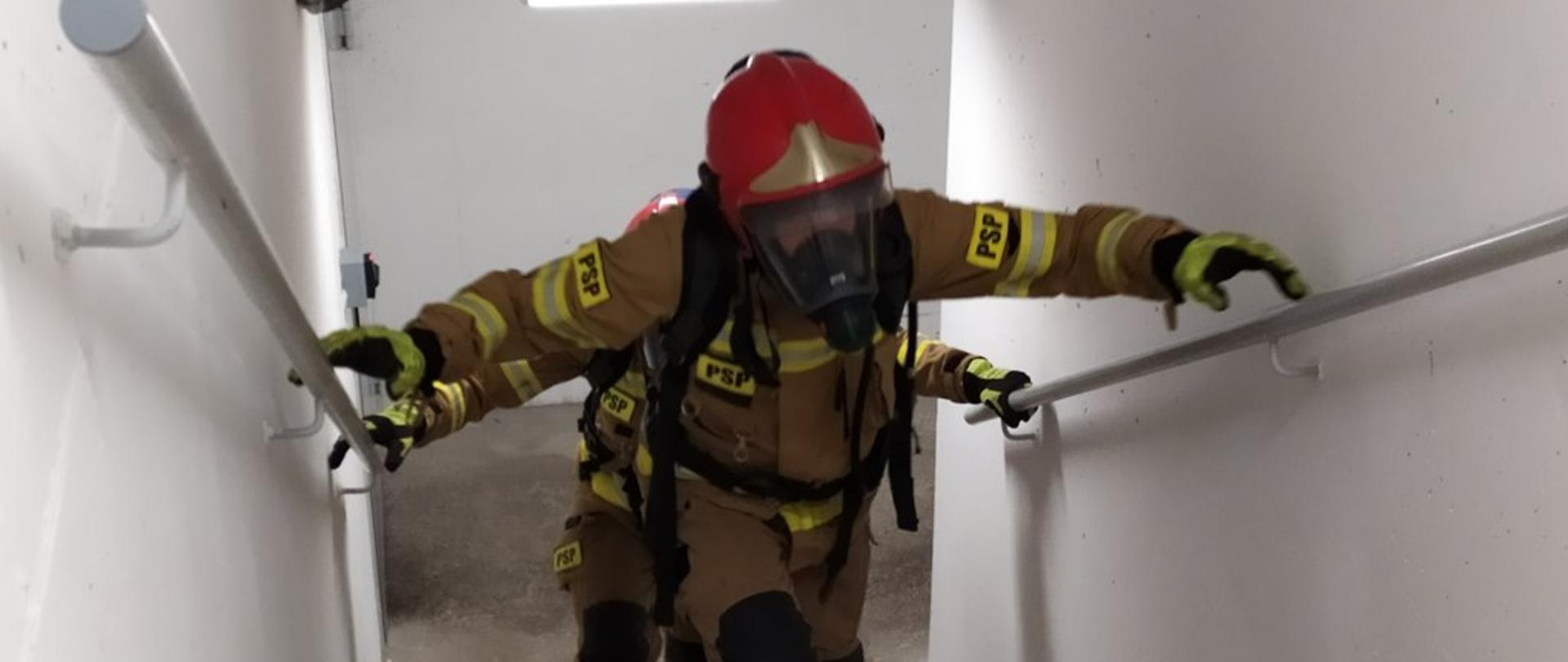 Ratownicy w ubraniach specjalnych z aparatami powietrznymi wbiegają po schodach na kolejne piętra.