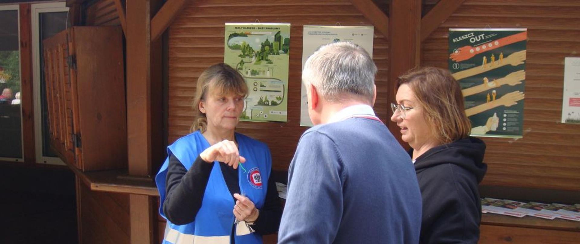 Na zdjęciu pracownik inspekcji sanitarnej pokazuje uczestnikom grzybobrania kleszczołapkę – przyrząd do usuwania kleszczy.