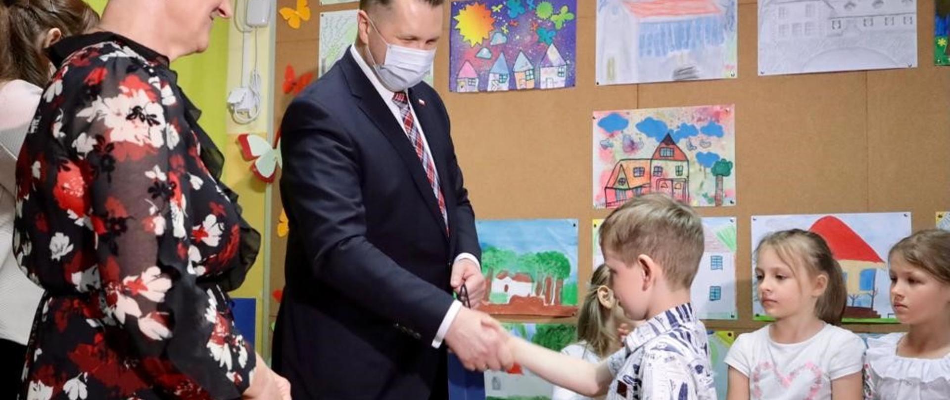 Minister Edukacji i Nauki Przemysław Czarnek w szkole wita się z dziećmi.