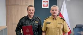 Komendant Powiatowy Państwowej Straży Pożarnej w Człuchowie st. bryg. Radosław Batruch stoi w gabinecie i wręcza akt mianowania na stanowisko dowódcy zmiany asp. Wojciechowi Kujszczyk.