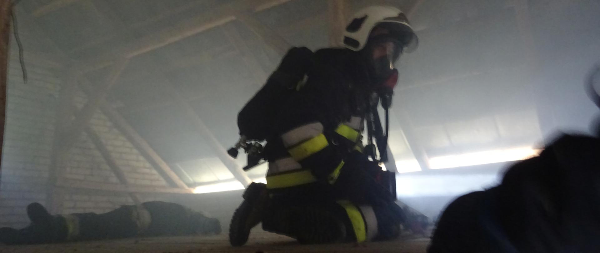 Na zdjęciu widać strażaka OSP idącego po poszkodowanego w zadymieniu.