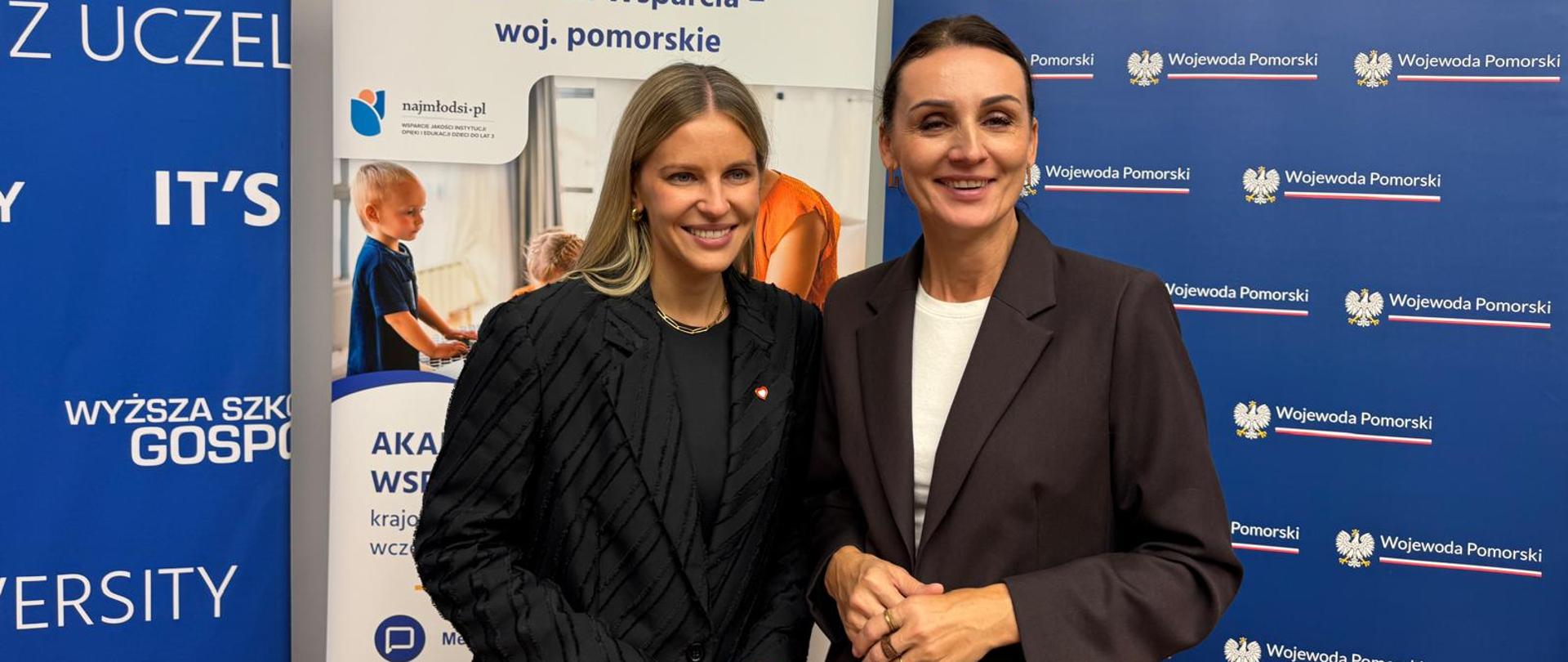 dwie kobiety stoją na tle tablicy z napisem Wojewoda Pomorski