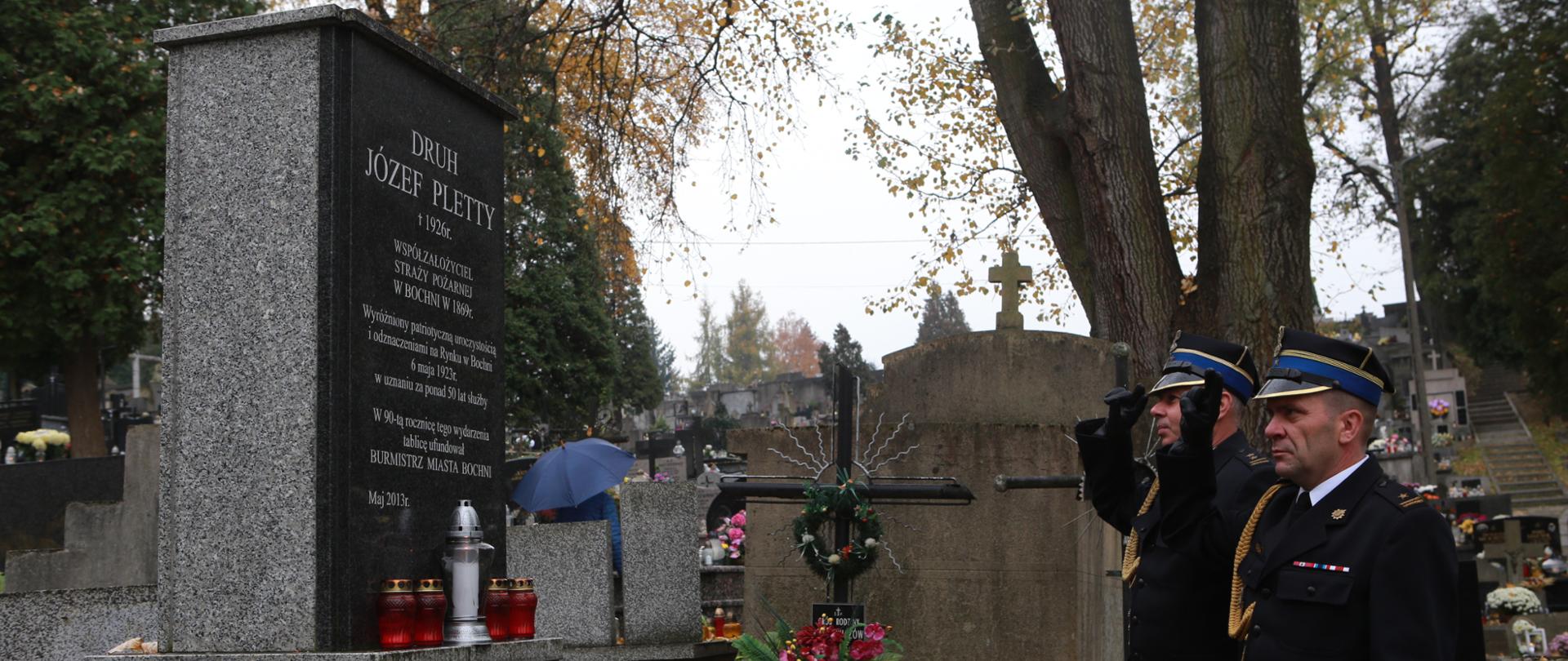 Pomnik z granitu na cmentarzu z inskrypcją Druh Józef Pletty 1926 r. współzałożyciel Straży Pożarnej w Bochni w 1869 r. Po prawej stronie pomnika 2 strażaków z Państwowej Straży Pożarnej w umundurowaniu wyjściowym oddają honory poprzez salutowanie zasłużonemu strażakowi. Na pomniku palą się znicze i znajdują się wiązanki kwiatów