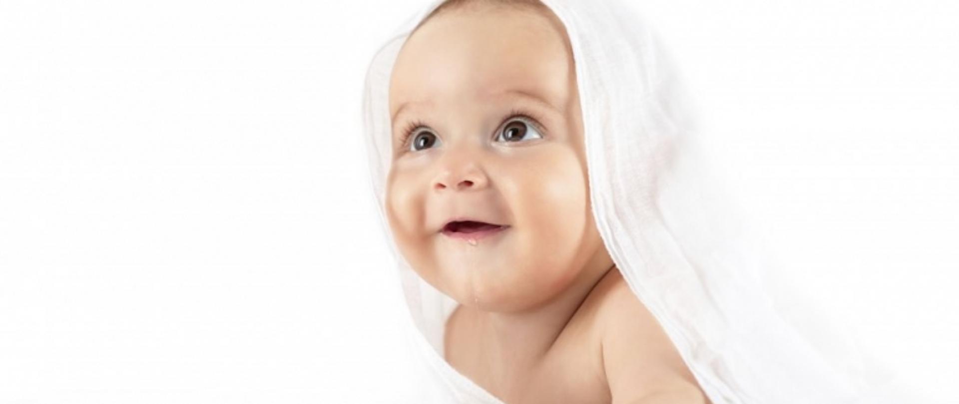 uśmiechnięte niemowlę przykryte pieluszką