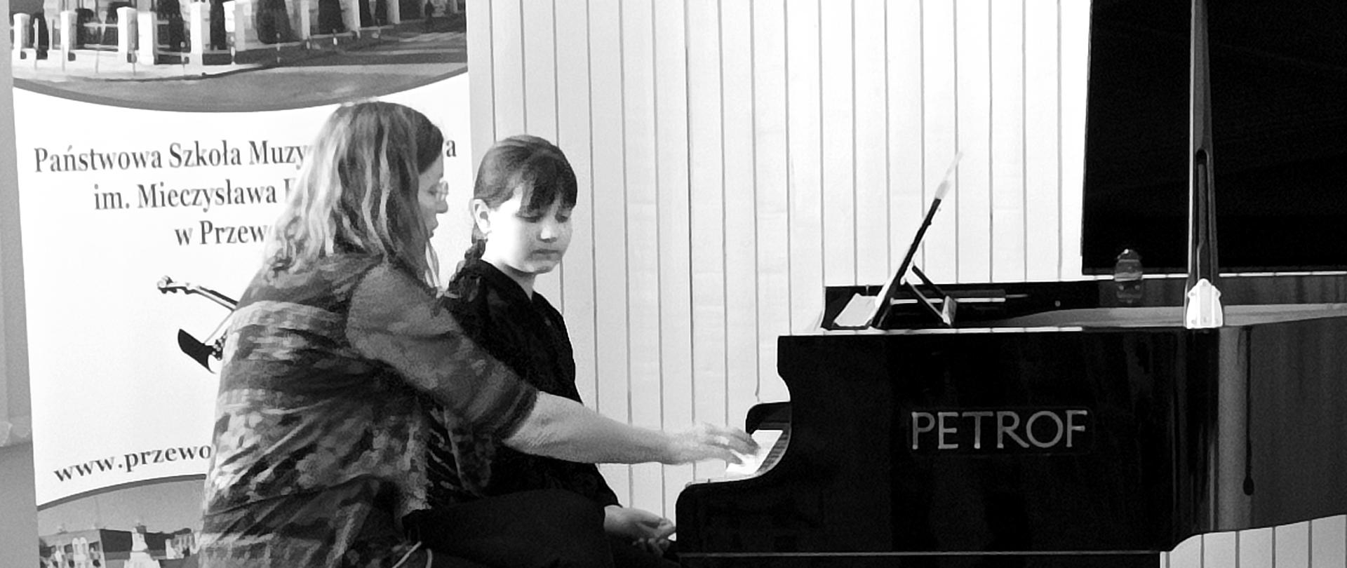 Prof. Magdalena Prejsnar-Wąsacz przy fortepianie z uczennicą udzielająca porad warsztatowych.