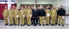 Pamiątkowe zdjęcie grupowe funkcjonariuszy PSP będących uczestnikami szkolenia dla kierowców pojazdów uprzywilejowanych (15 osób) w towarzystwie Zastępcy Komendanta CS PSP oraz dwóch funkcjonariuszy CS PSP