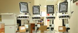 Cztery urządzenia medyczne z ekranami na kółkach i z naklejkami Caritas i Polska pomoc