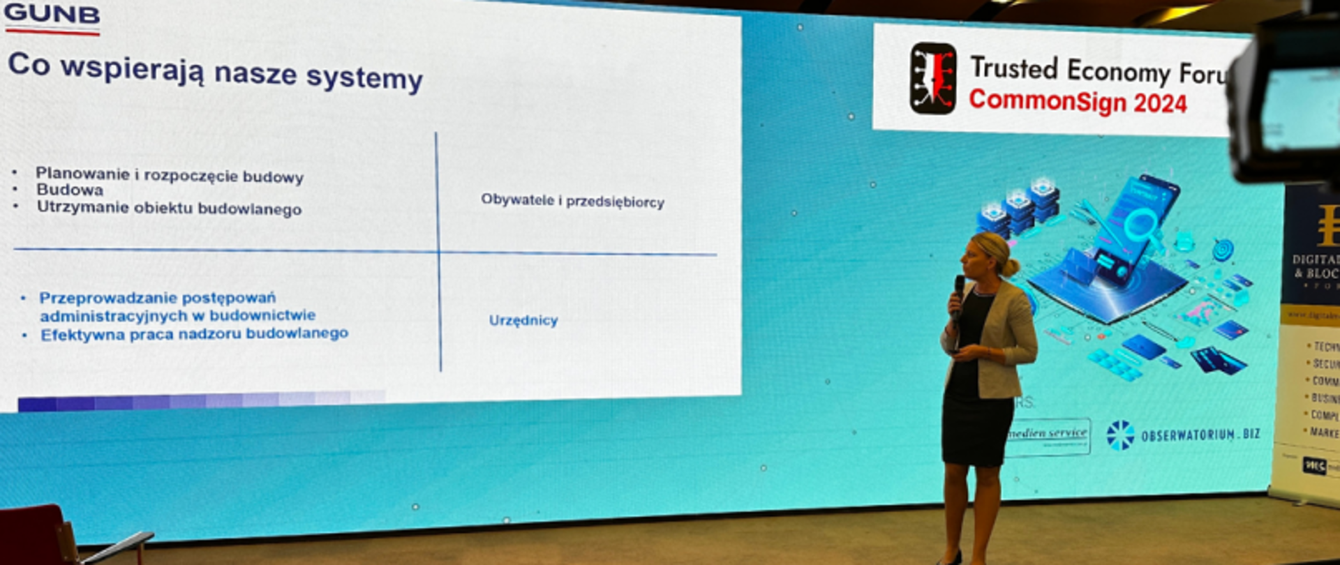 Osoba prezentująca na scenie z mikrofonem podczas Trusted Economy Forum, CommonSign 2024; na ekranie widoczny wykres z obszarami: „Planowanie i rozpoczęcie budowy”, „Budowa”, „Utrzymanie obiektu budowlanego”, „Przeprowadzanie postępowań administracyjnych w budownictwie”, „Efektywna praca nadzoru budowlanego”.
