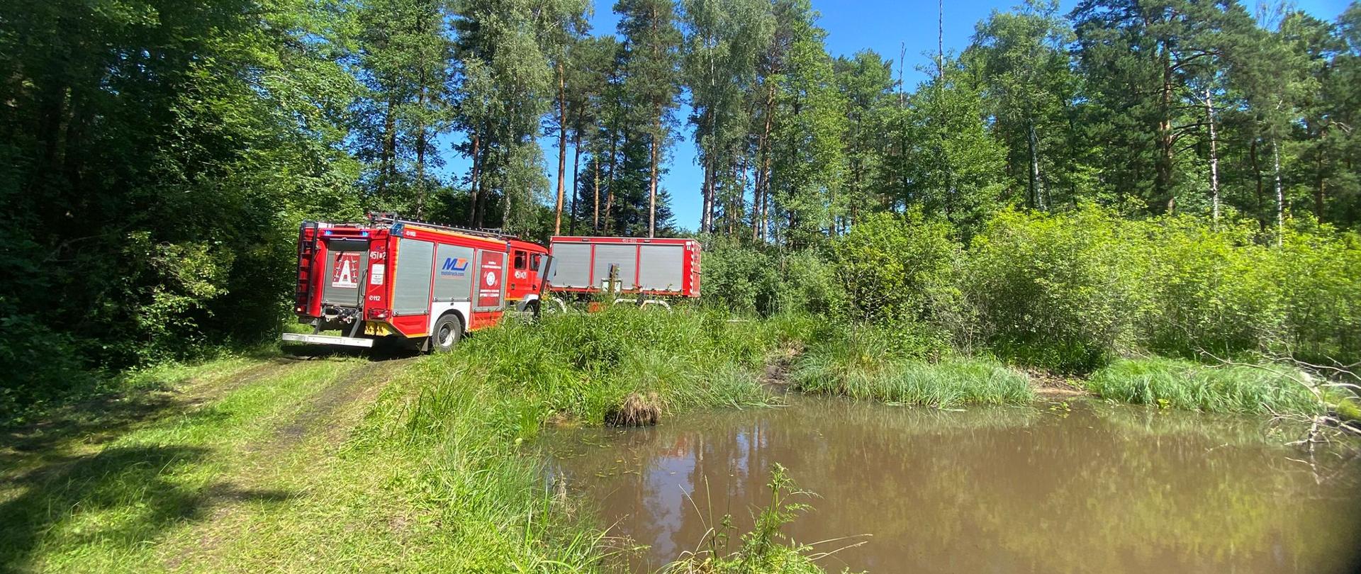 Na zdjęciu widoczne są wozy strażackie przy zbiorniku wodnym