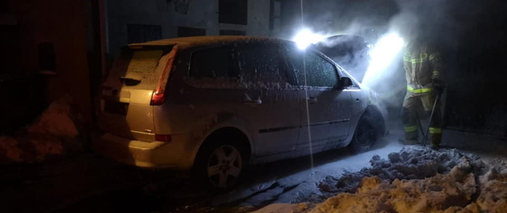 Strażak stojący przy palącym się samochodzie