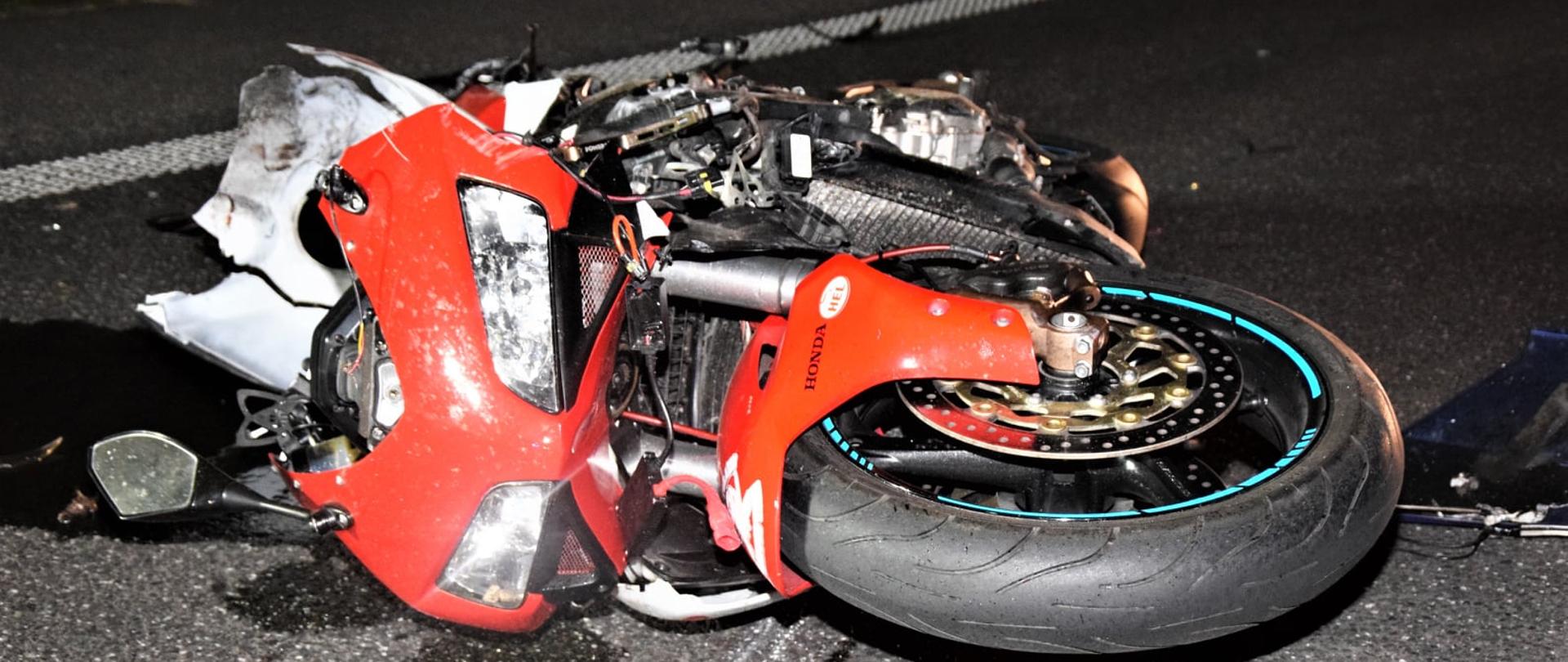 Widać leżący uszkodzony motocykl na drodze