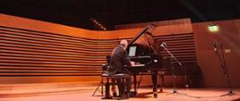 Artysta gra na fortepianie na scenie sali koncertowej PSM w Jastrzębiu-Zdroju