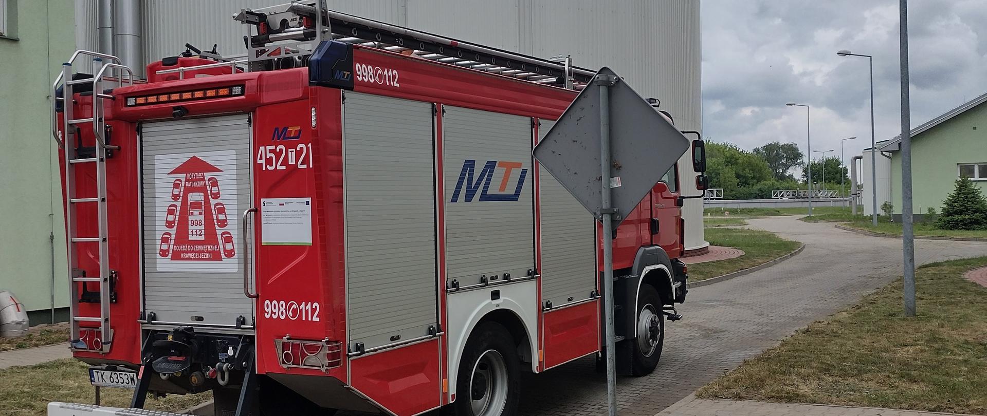 Samochód gaśniczy na tle wysokiego silosu na terenie oczyszczalni