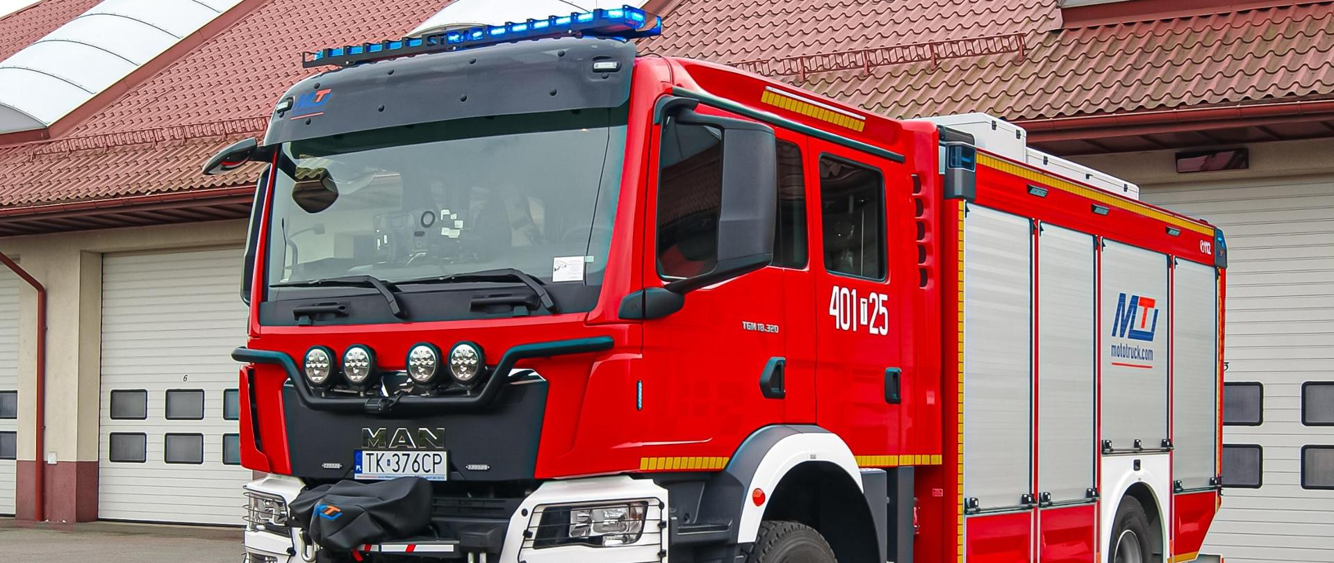 Samochód pożarniczy na tle garaży. 