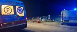 Na zdjęciu widoczny jest zniszczony pojazd osobowy, który podczas zdarzenia wypadł z drogi, tył pojazdu policji oraz tył pojazdu ZRM. pomiędzy pojazdami widoczna jest torba medyczna.