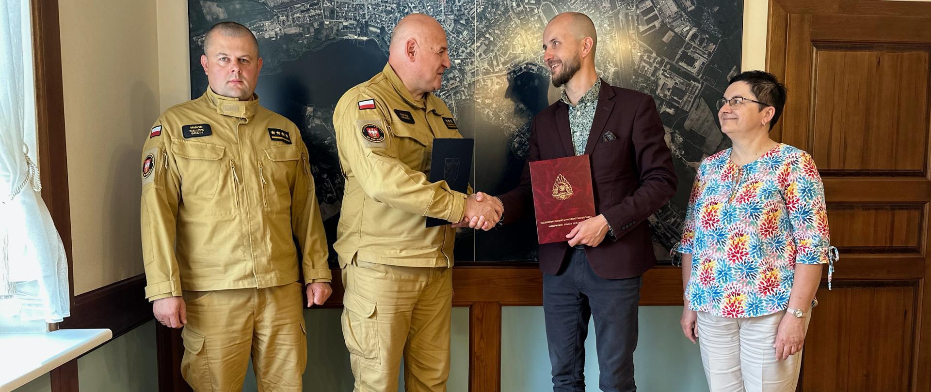 Zdjęcie przedstawia wręczenie podpisanej umowy dotycząca wsparcia finansowego dla KP PSP w Wałczu która odbyła się w siedzibie Urzędu Miasta Wałcza