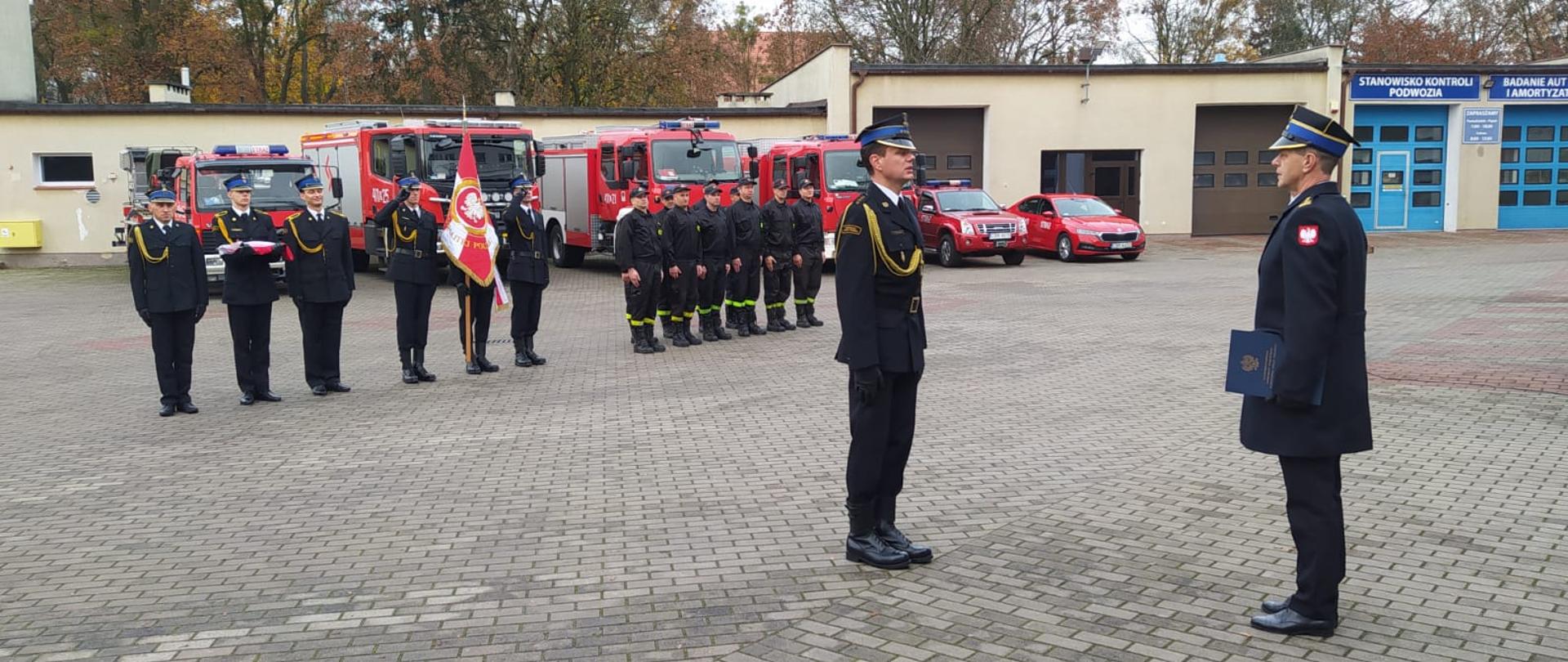 Zdjęcie przedstawia złożenie meldunku Komendantowi Powiatowemu PSP w Brodnicy st. bryg. Andrzejowi Góreckiemu. W tle strażacy PSP w Brodnicy oraz samochody Komendy Powiatowej.