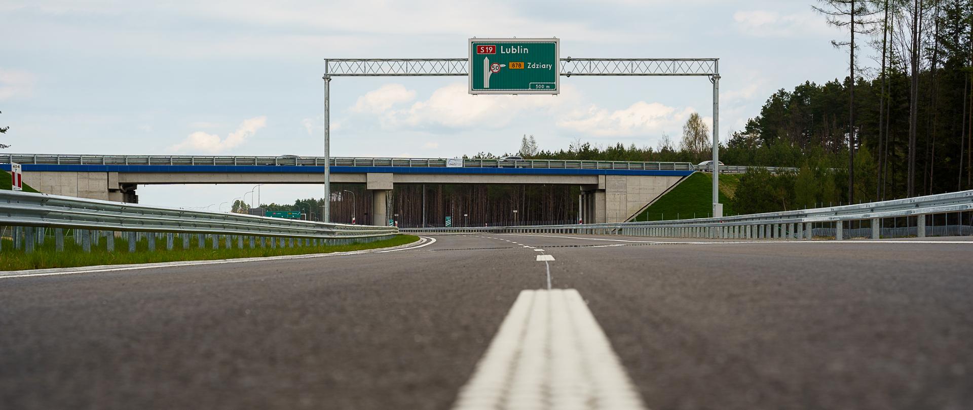 Na zdjęciu droga ekspresowa S19 w tle widać wiadukt nad drogą oraz znak z zaznaczonym kierunkiem Lublin