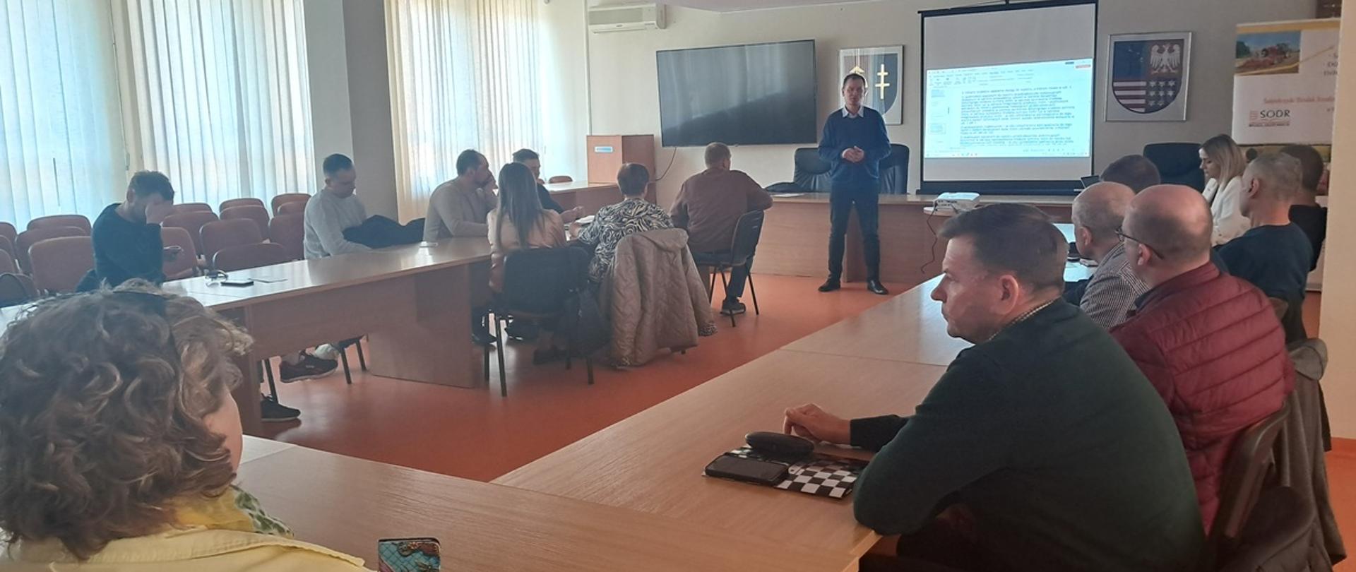 Zgromadzeni rolnicy siedzą za stołem i wysłuchują wykładu.