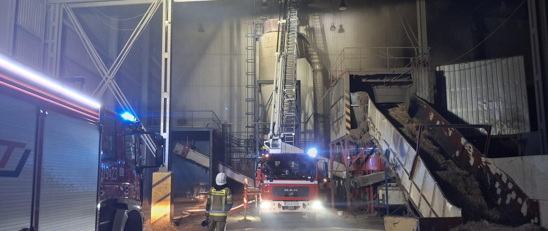 samochody strażackie oraz strażak w hali pelletu
