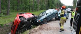 3 samochody osobowe na poboczu drogi po zderzeniu, w tle służby ratownicze