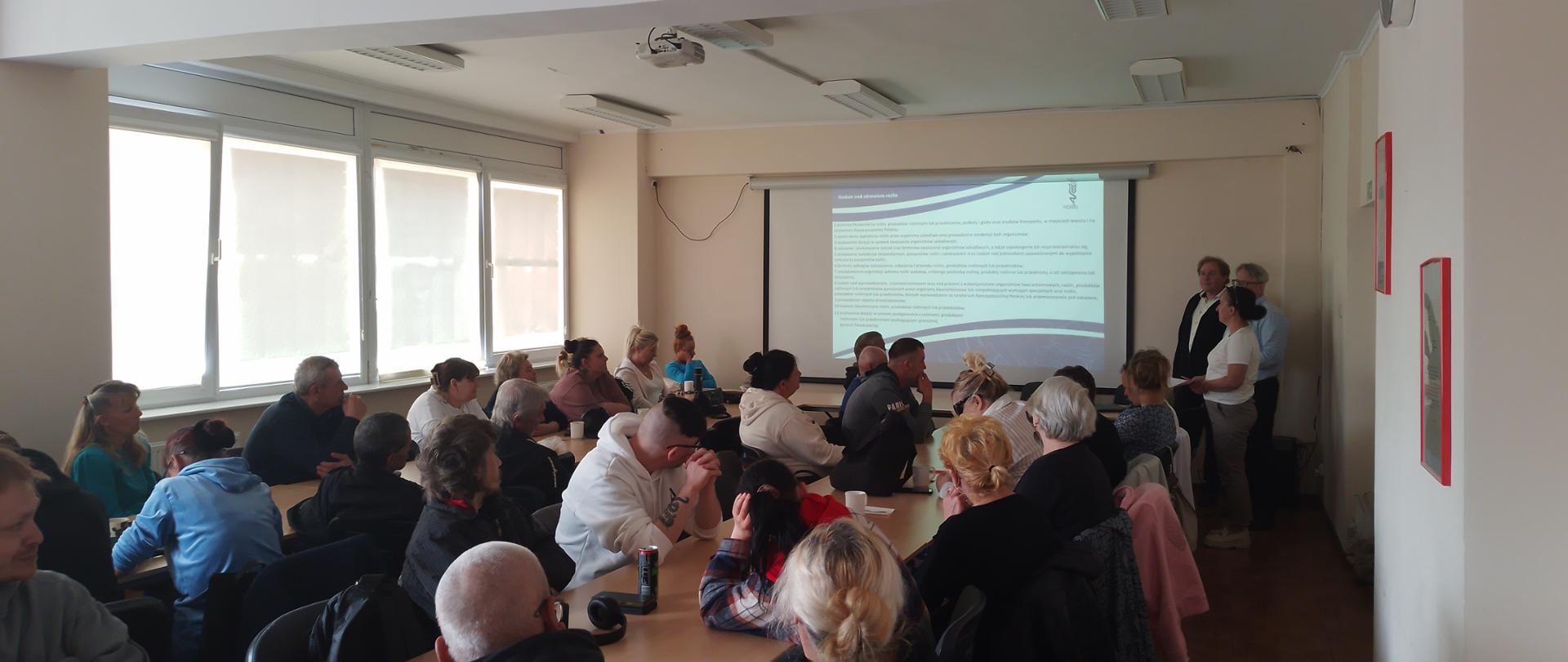 Zdjęcie przedstawia salę konferencyjną wypełnioną ludźmi. Pracownicy WIORiN w Łobzie prowadzą prelekcję dla zgromadzonych ludzi.