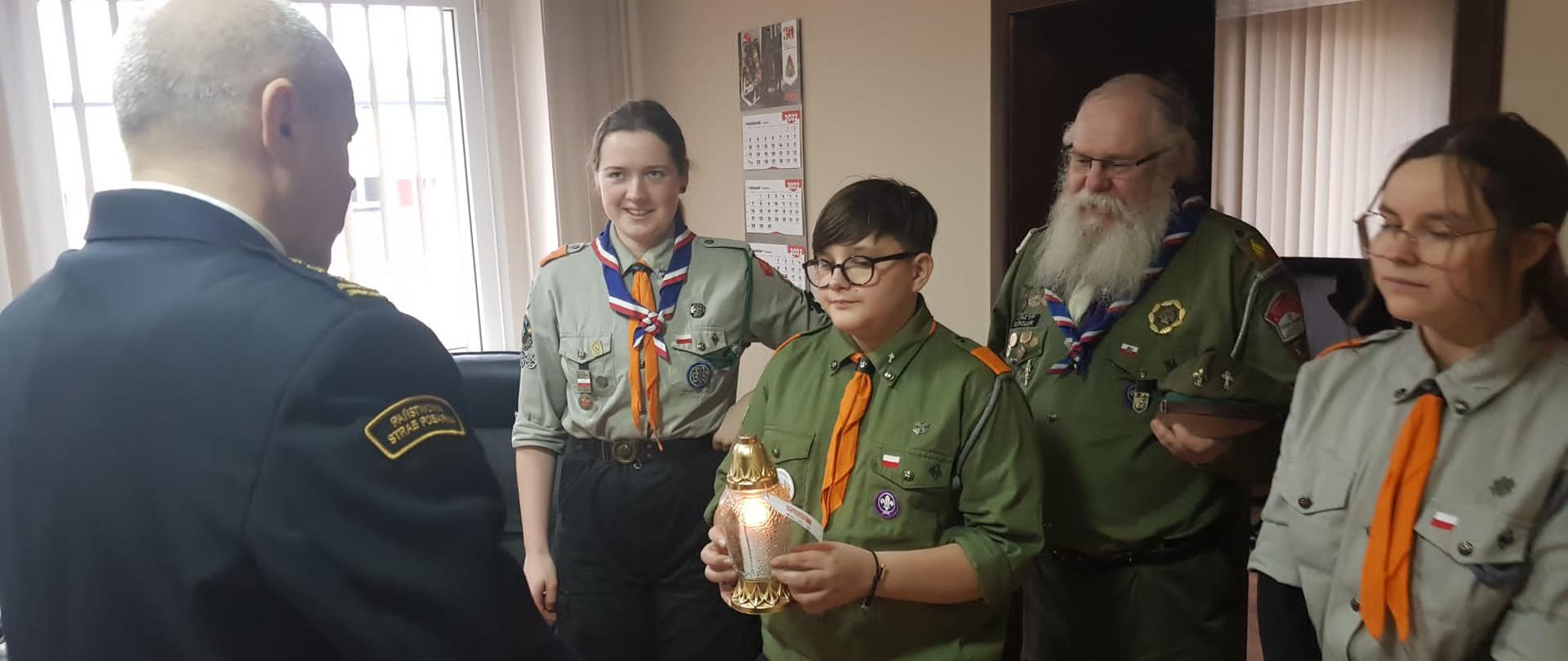 Na zdjęciu widać harcerzy przekazujących Betlejemskie Światło Pokoju Komendantowi Powiatowemu PSP 