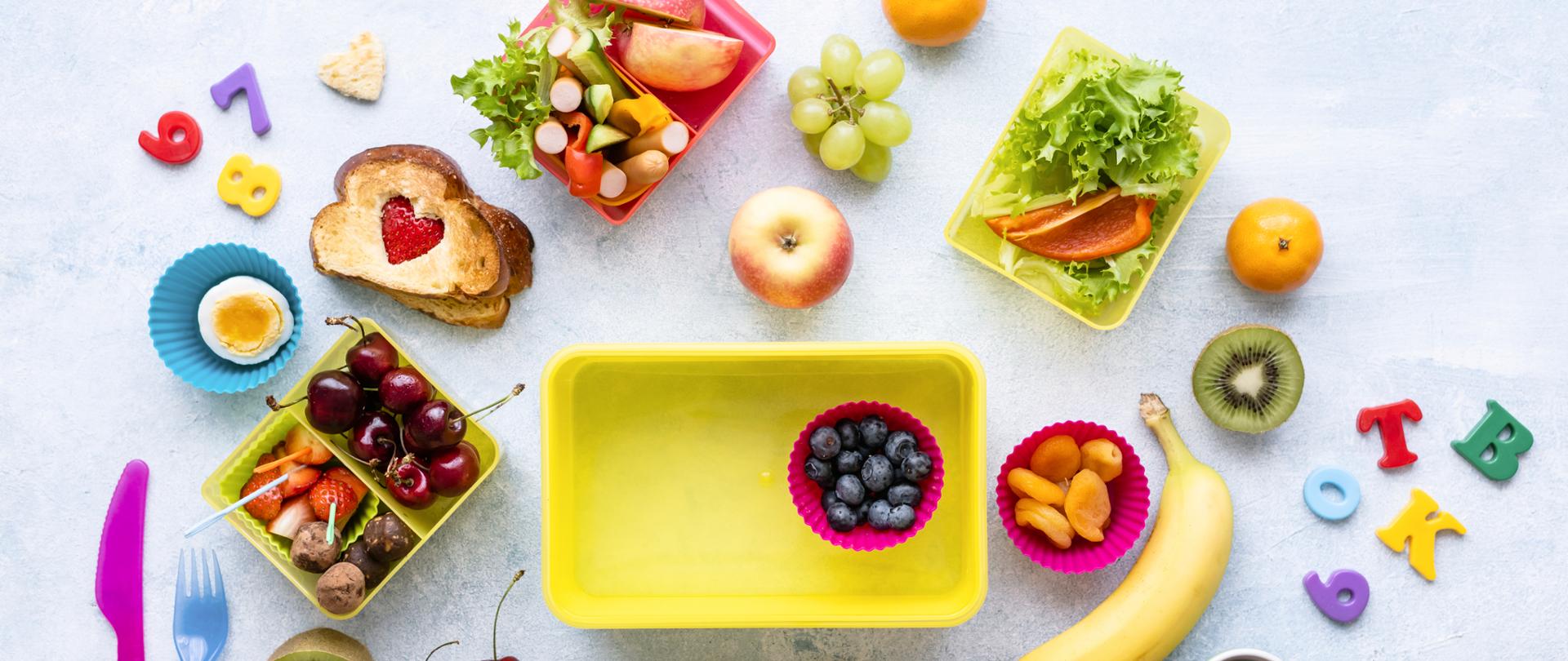 Zdjęcie przedstawia, co można włożyć do śniadaniówki dziecka, aby było zdrowo i aby posiłek dostarczał energii na długo. Może to być jako, twarożek, a także owoce i warzywa do pochrupania.