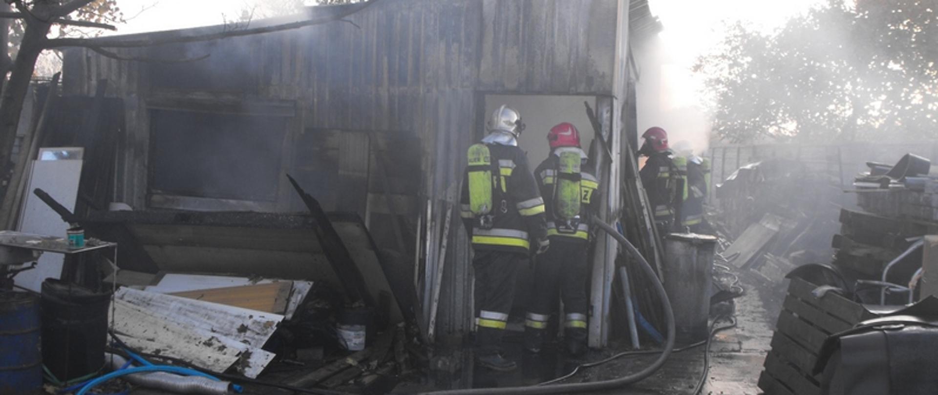 Zdjęcie przedstawia strażaków przy budynku gospodarczym