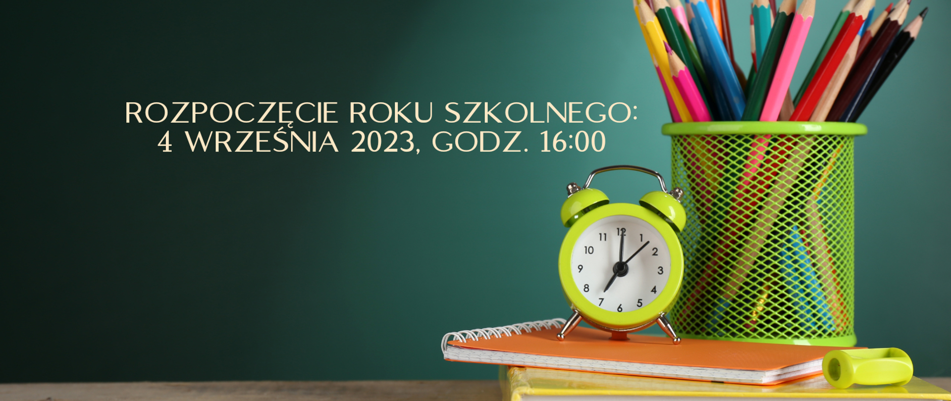 Na drewnopodobnym blacie leży żółta książka, na niej pomarańczowy zeszyt, limonkowa temperówka i zielony pojemnik z kolorowymi kredkami. Na zeszycie stoi limonkowy retro-budzik. Tłem jest ściana w kolorze butelkowej zieleni.