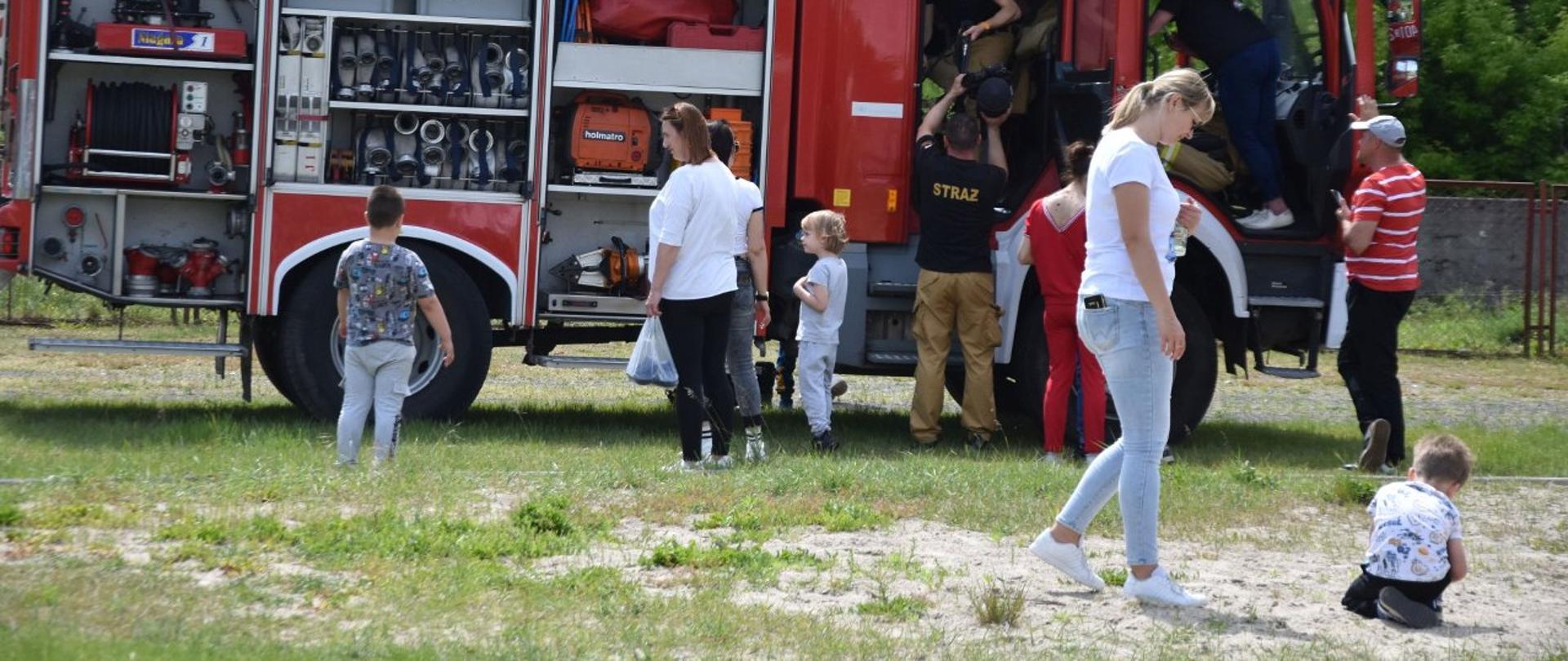 Strażacy pokazujący sprzęt znajdujący się w samochodzie pożarniczym.jp