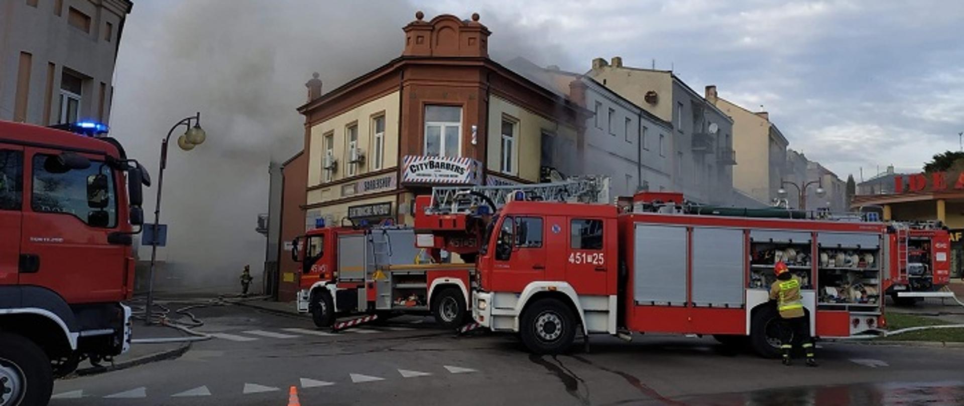 Pożar Kamienicy kłęby dymu widok z ulicy. W oddali wóz strażacki i drabina SD37. 