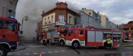 Pożar Kamienicy kłęby dymu widok z ulicy. W oddali wóz strażacki i drabina SD37. 