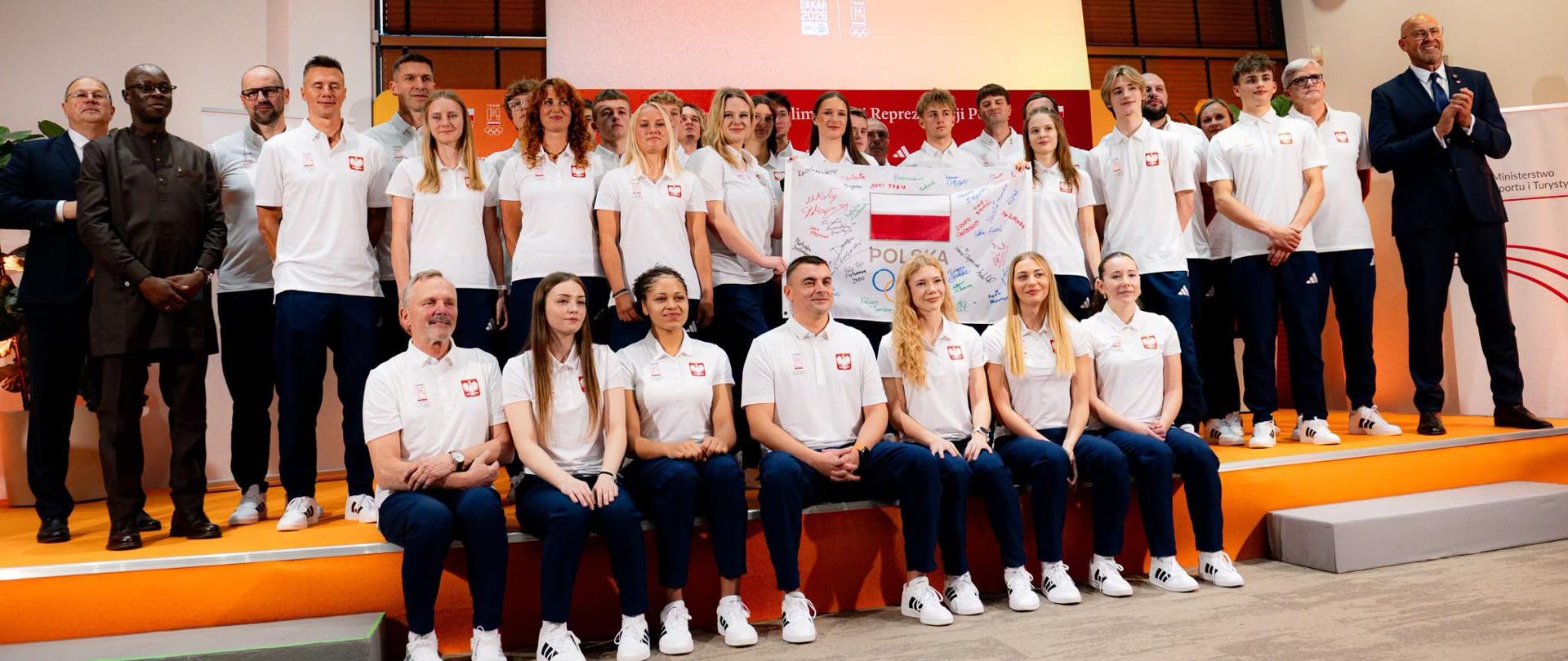 Zbiorowe zdjęcie reprezentacji Polski na IV Młodzieżowe Igrzyska Olimpijskie Dakar 2026 zrobione podczas uroczystości ślubowania. Z prawej strony stoi minister sportu i turystyki Jakub Rutnicki.