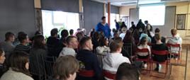W dużej sali kilkudziesięciu uczniów słucha prelegentki.
