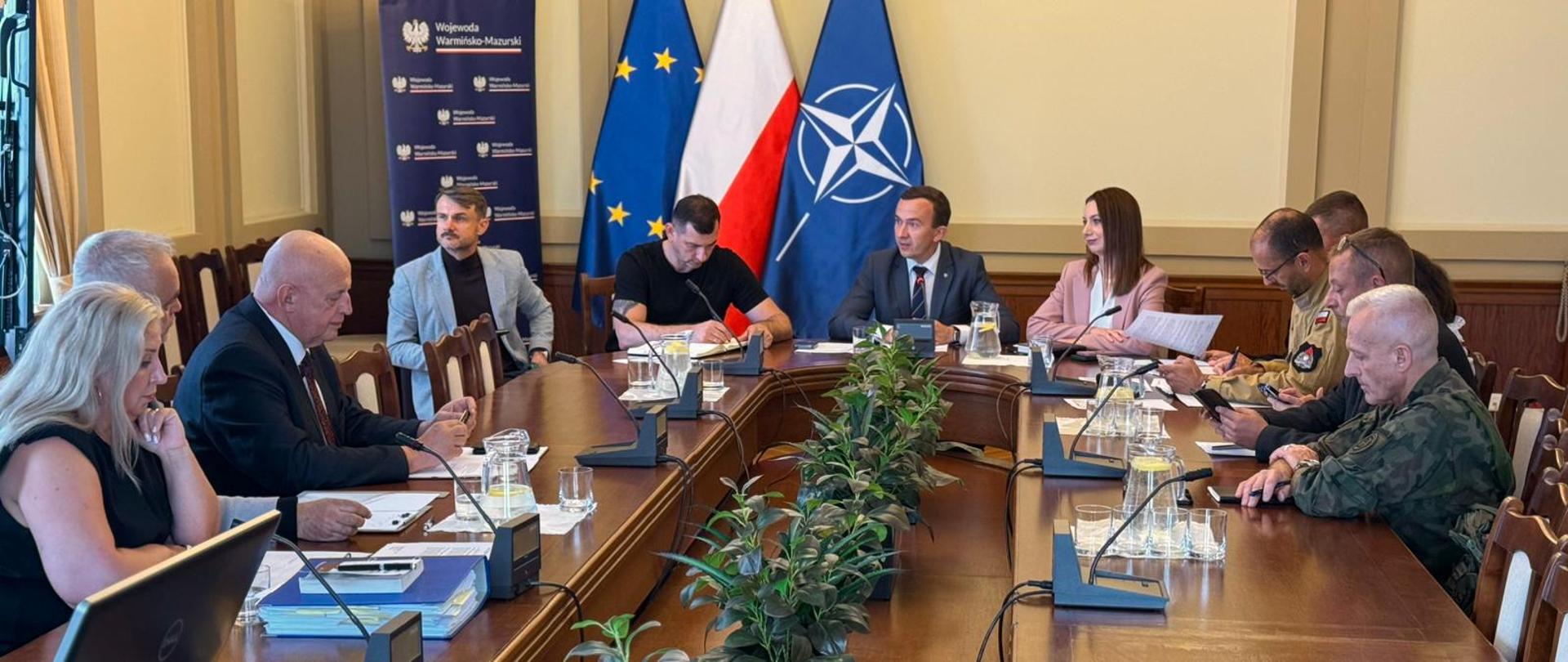 grupa przedstawicieli różnych instytucji siedzą przy stole konferencyjnym, prowadzą dyskusję 