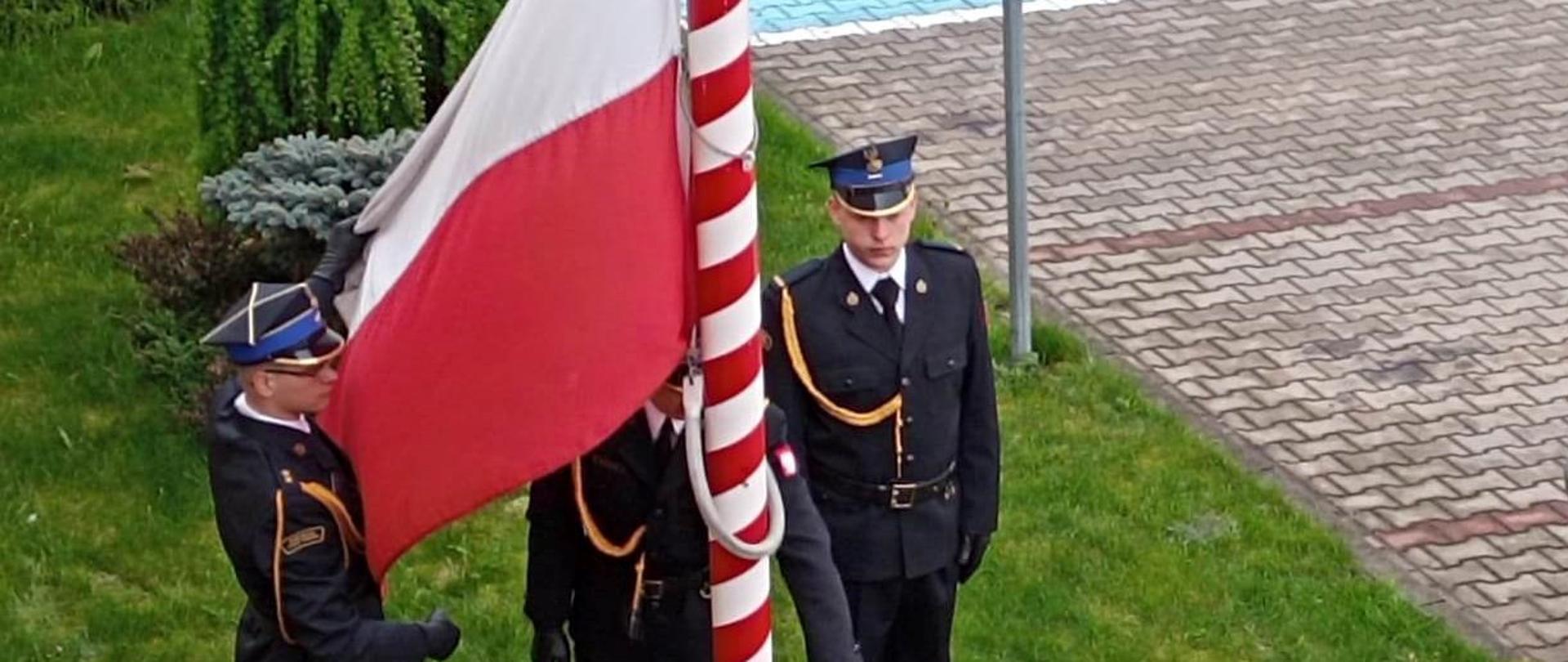 Dzień flagi RP. Poczet flagowy dokonuje podnoszenia flagi państwowej na masz. Dowódca pocztu przytrzymuje rozwiniętą flagę. Poczet wystepuje w umundurowaniu wyjściowym.