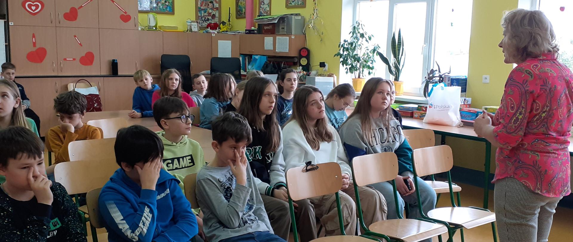 Zdjęcie dzieci w świetlicy szkolnej słuchających wykładu pani pielęgniarki.