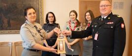 harcerka oraz komendant wojewódzki trzymają betlejemskie światło pokoju, za nimi stoją trzy harcerki