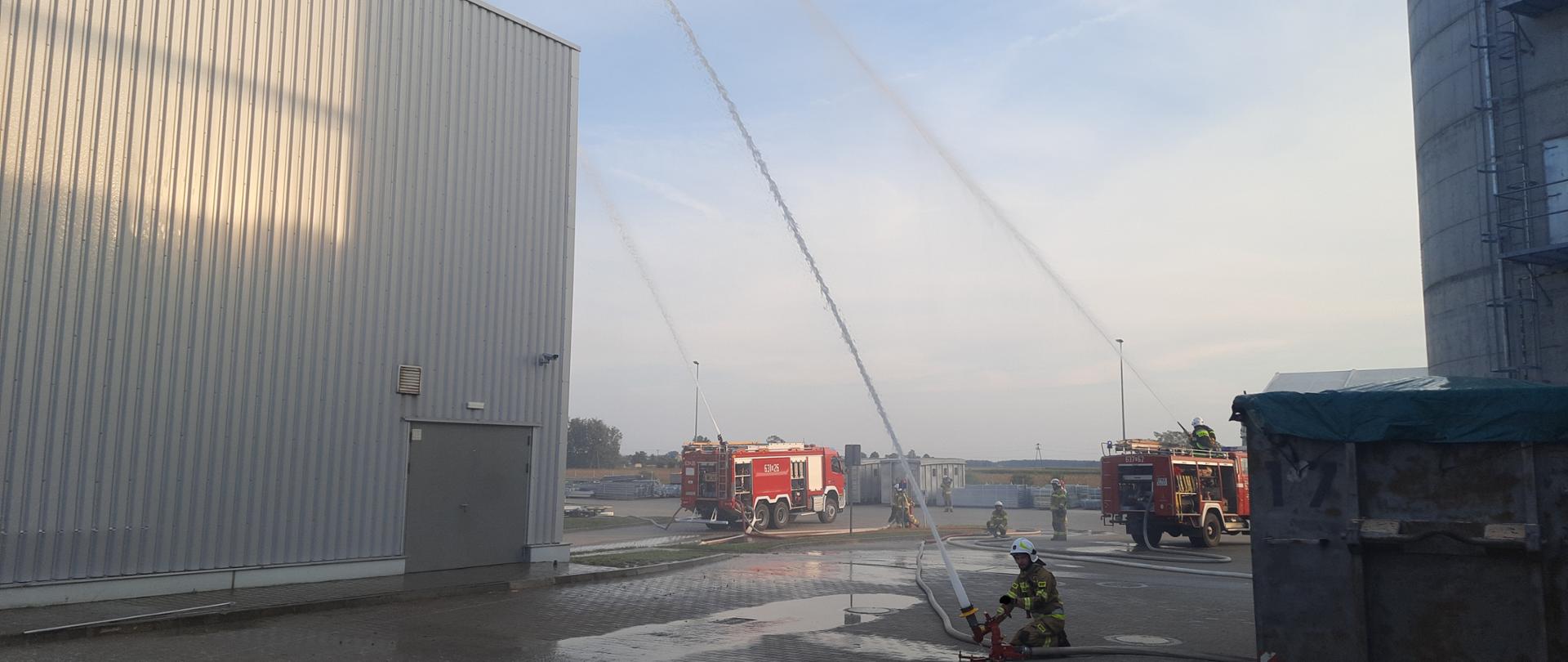 Na zdjęciu widać strażaków podających wodę z działek przenośnych oraz wozy strażackie 