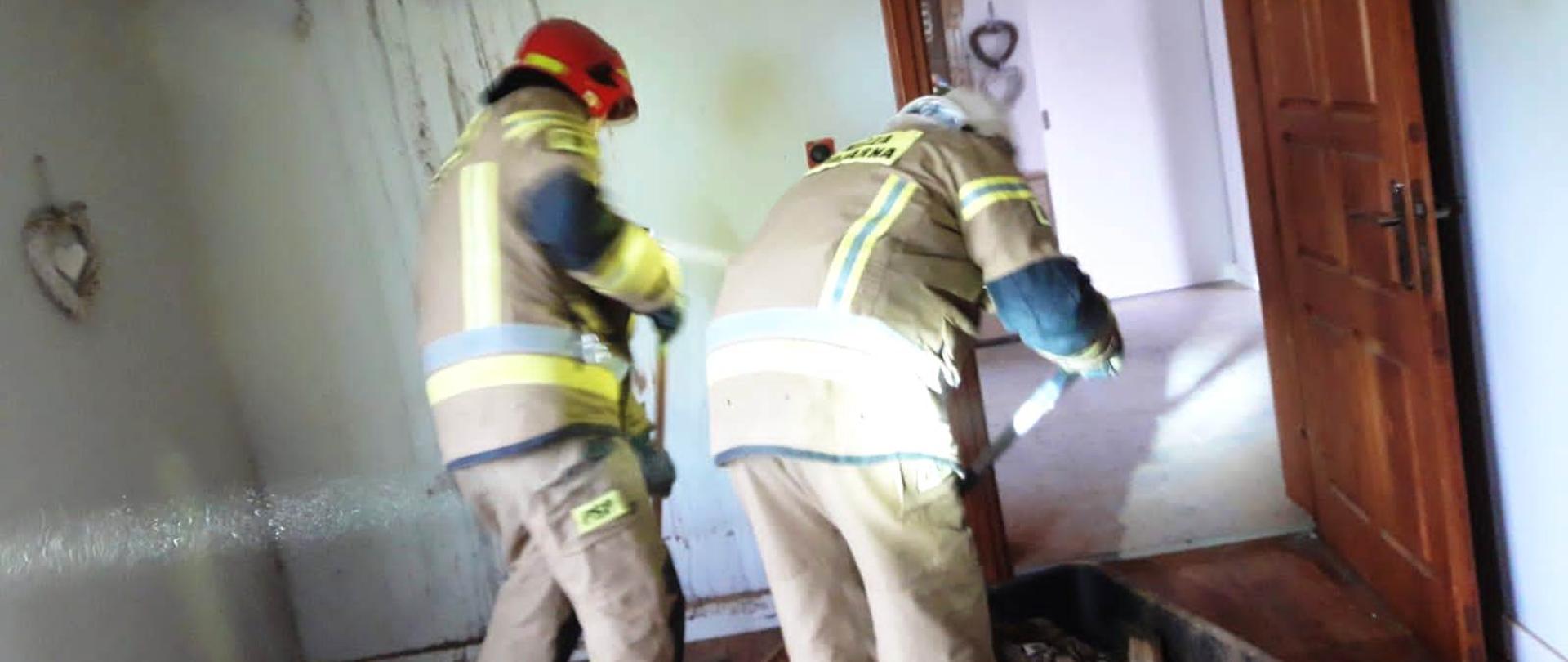 Strażacy prowadzący działania wewnątrz budynku.