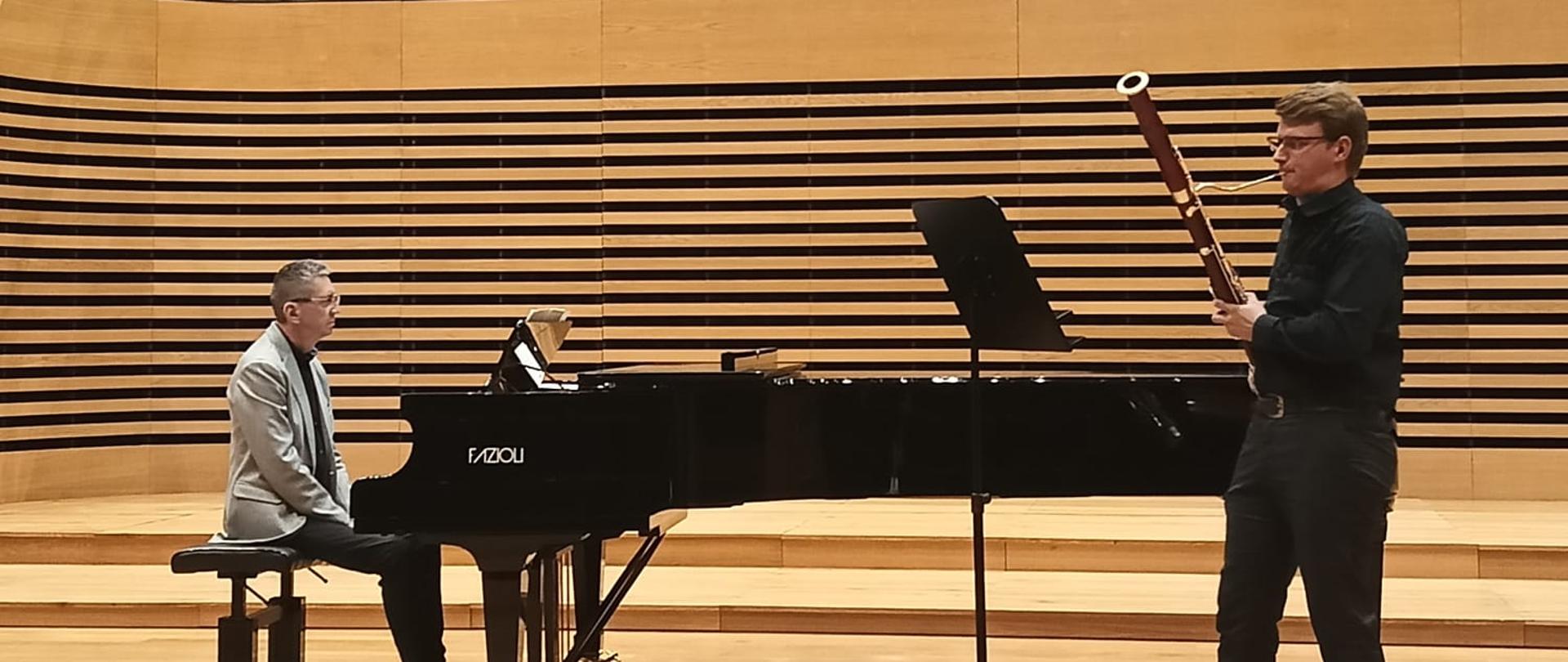 Nastolatek gra na fagocie, mężczyzna akompaniuje mu na fortepianie.